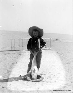 Tom Tate with drum fish stands in front of the 1900 glider